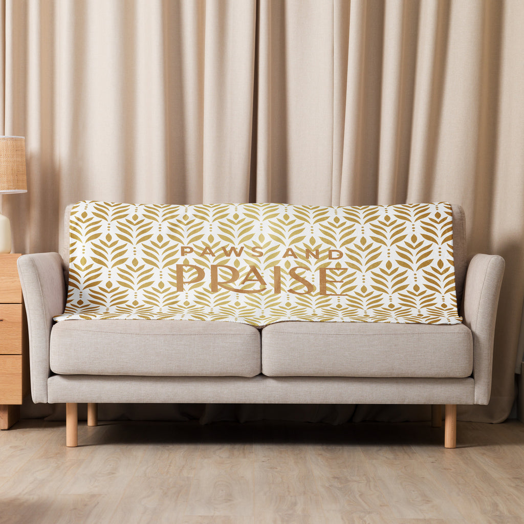 Sherpa blanket featuring a gold leaf pattern and “Paws and Praise” lettering in warm tones, a faith-inspired design that symbolizes gratitude, comfort, and the love between pets and their owners.
