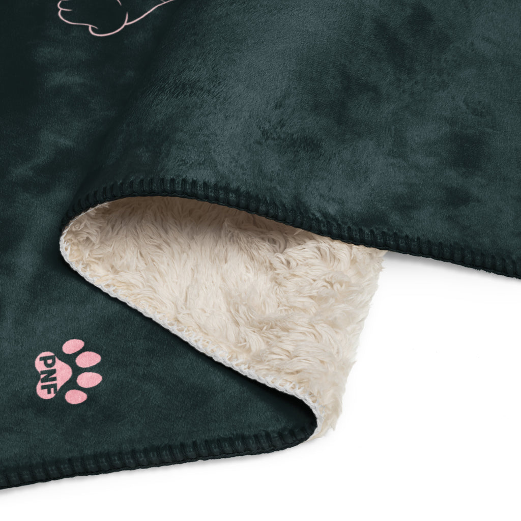 Close up view of forest green sherpa blanket with pink drawings of cats and dogs with the phrase, " God's Little Helpers". 