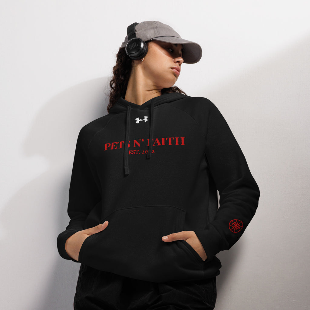 Lifestyle shot – Woman wearing Under Armour Pets N’ Faith Hoodie with hands in pocket and gray cap