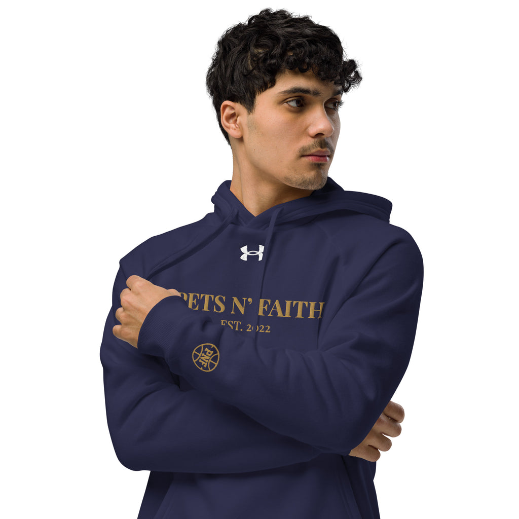 Man wearing navy blue Under Armour Pets N’ Faith Hoodie with gold text and sleeve emblem