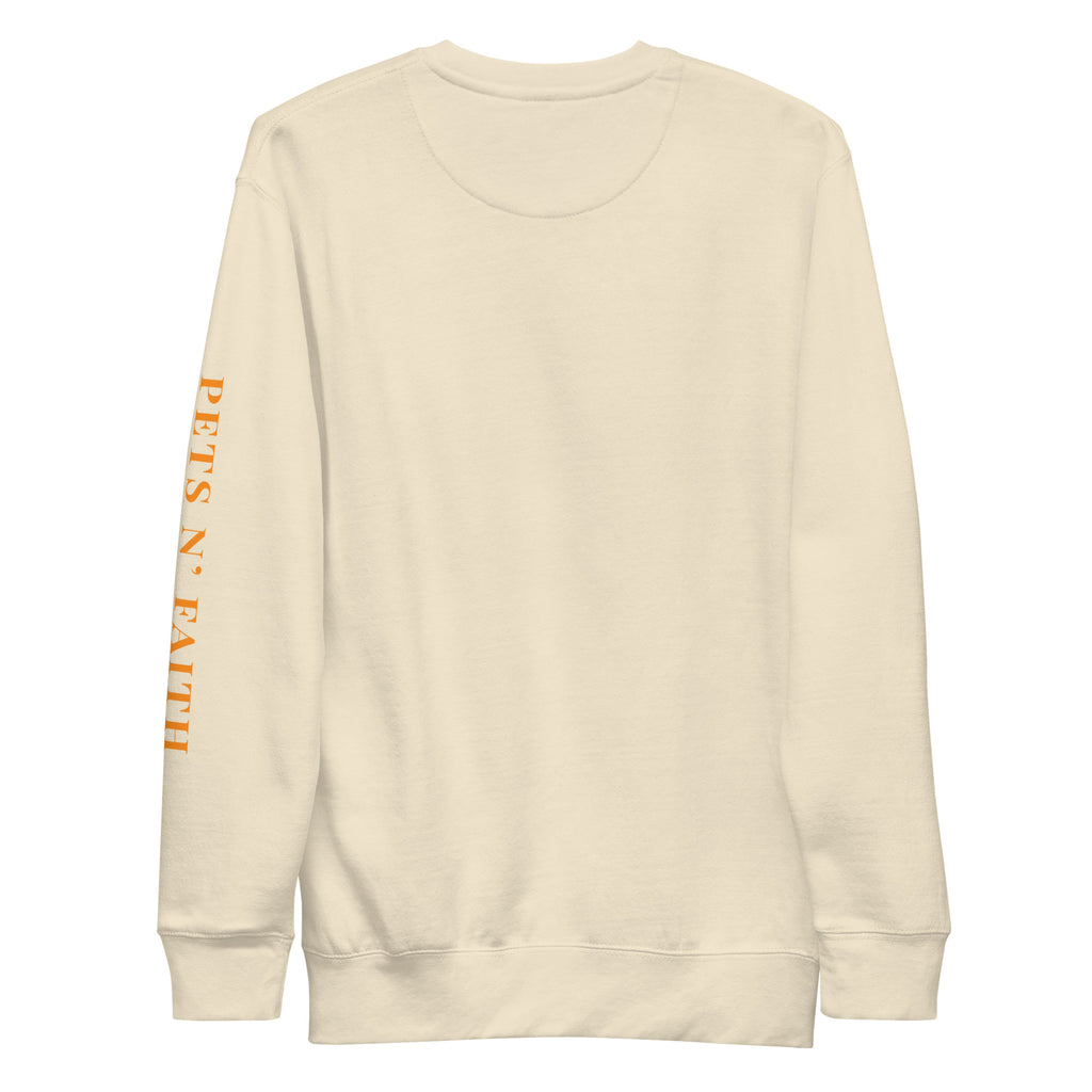 Bone colored unisex sweatshirt with a retro sunset-style paw print and PETS N’ FAITH text on the sleeve.