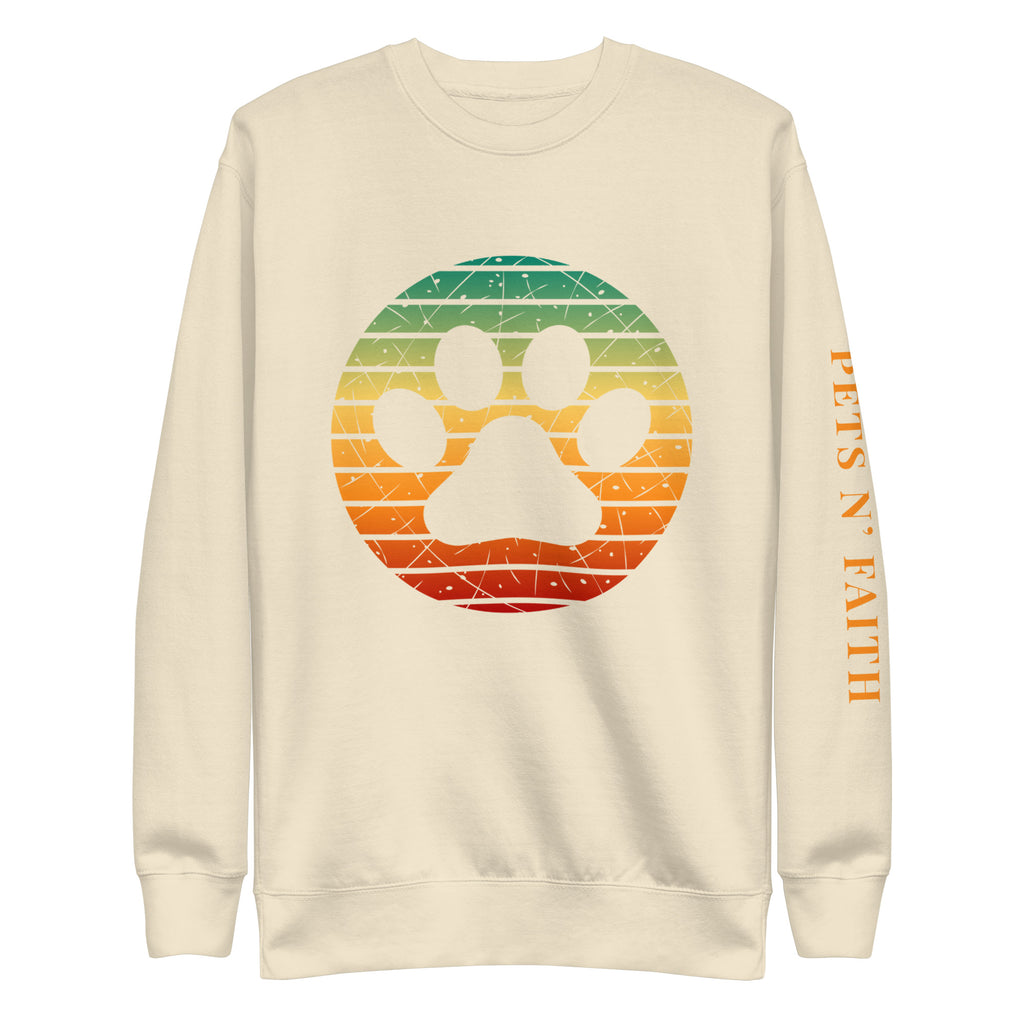 Bone colored unisex sweatshirt with a retro sunset-style paw print and PETS N’ FAITH text on the sleeve.