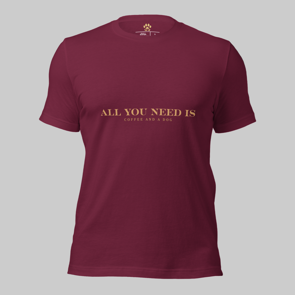 Maroon unisex T-shirt with the text ‘All You Need Is Coffee and a Dog’ in warm gold lettering