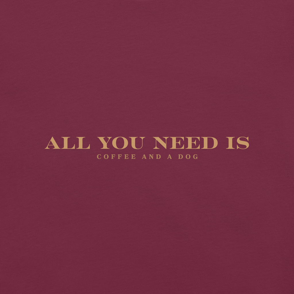 Maroon unisex T-shirt with the text ‘All You Need Is Coffee and a Dog’ in warm gold lettering