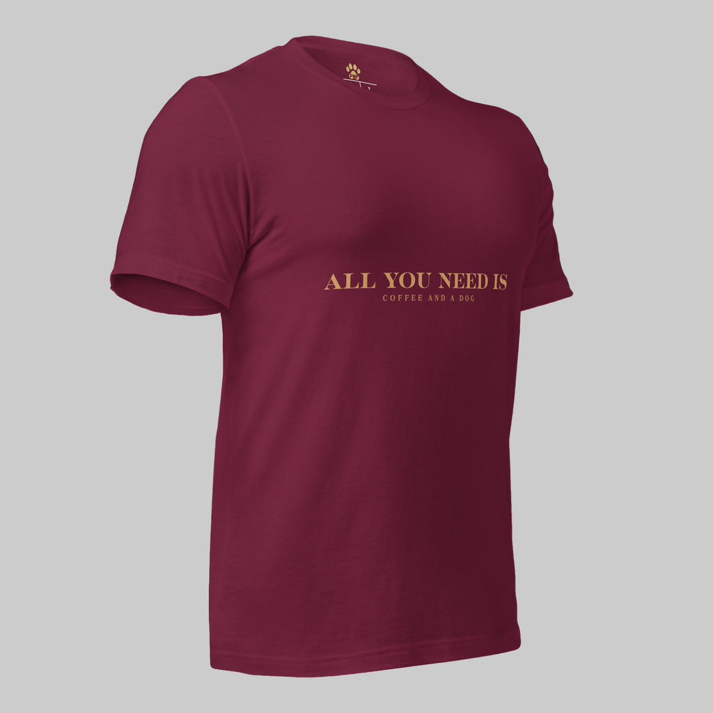 Maroon unisex T-shirt with the text ‘All You Need Is Coffee and a Dog’ in warm gold lettering