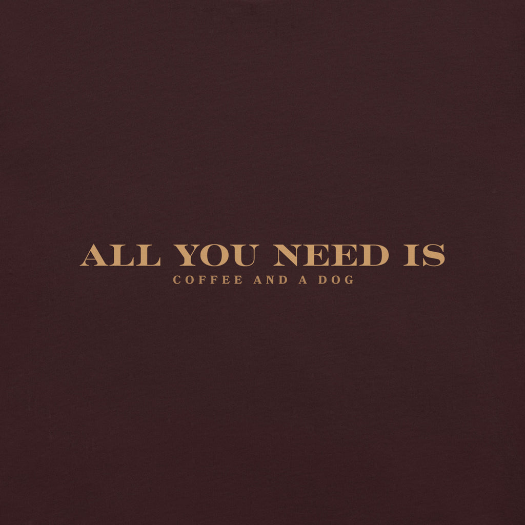 Oxblood unisex T-shirt with the text ‘All You Need Is Coffee and a Dog’ in warm gold lettering