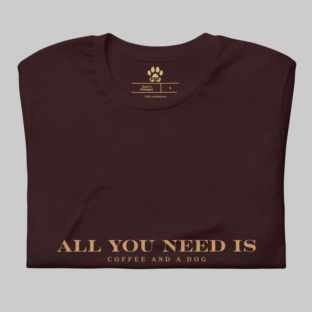 Oxblood unisex T-shirt with the text ‘All You Need Is Coffee and a Dog’ in warm gold lettering
