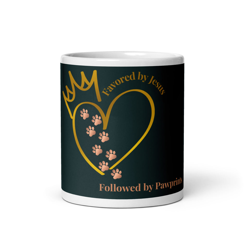 White glossy mug with a teal background. The graphic is a gold heart with a gold crown on top. The phrase is, " Favored by Jesus, Followed by Paw prints".  Small pet paw prints are walking through the heart graphic. 