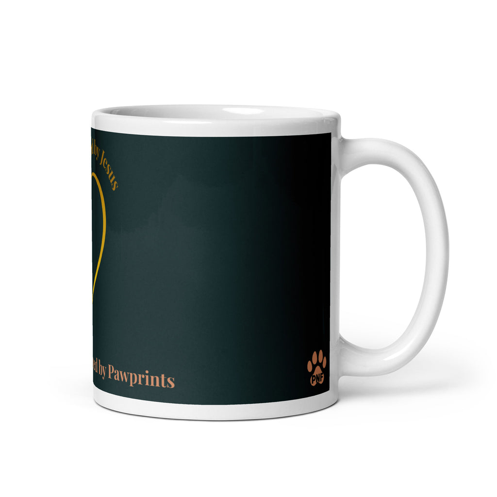 Side view of white glossy mug with a teal background. The graphic is a gold heart with a gold crown on top. The phrase is, " Favored by Jesus, Followed by Paw prints".  Small pet paw prints are walking through the heart graphic. 
