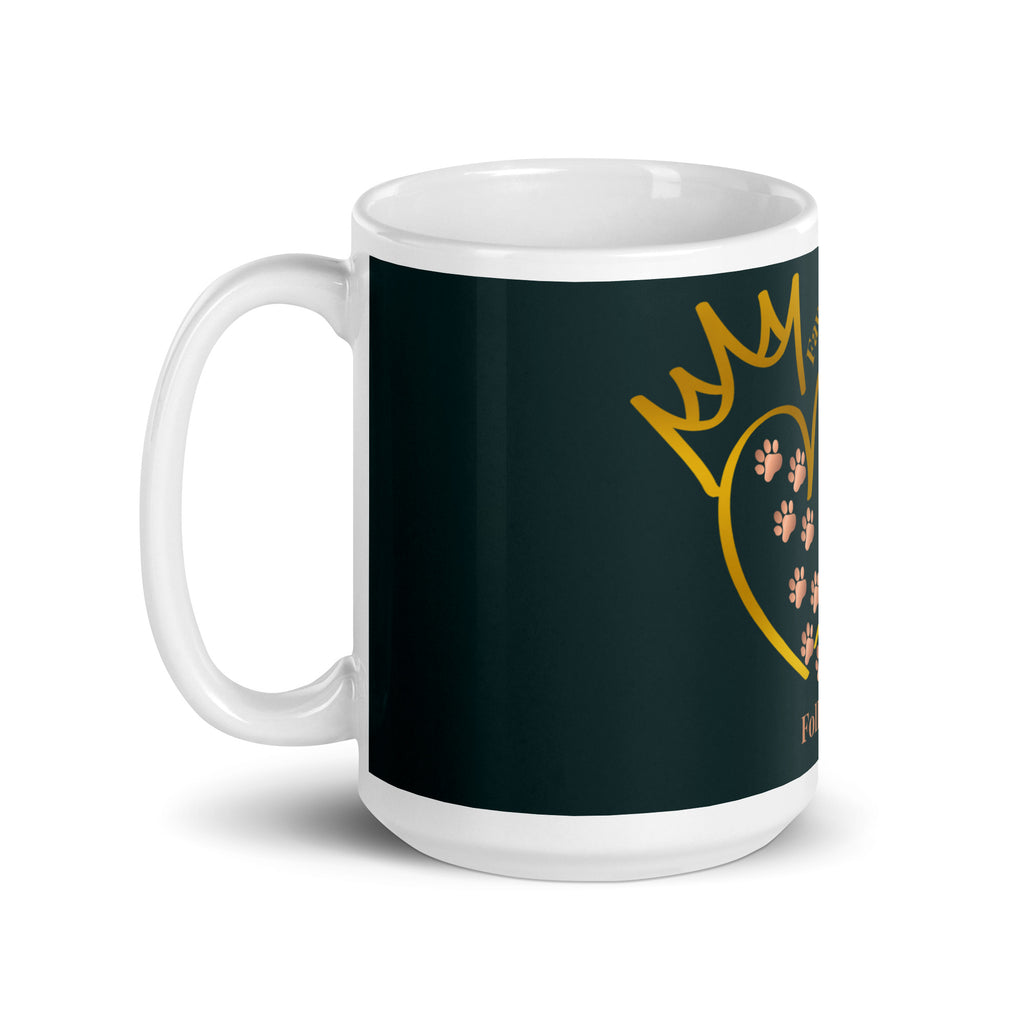 Side view of white glossy mug with a teal background. The graphic is a gold heart with a gold crown on top. The phrase is, " Favored by Jesus, Followed by Paw prints".  Small pet paw prints are walking through the heart graphic. 