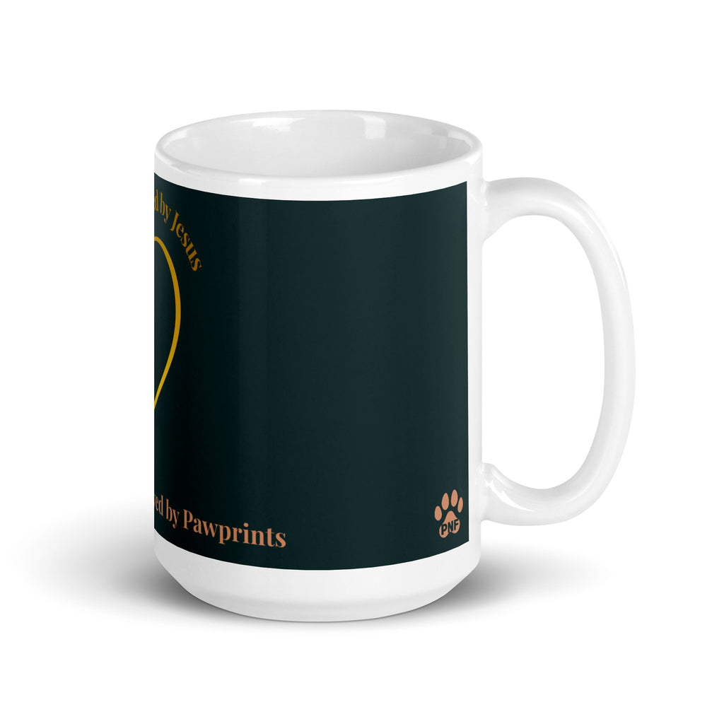 Side view of white glossy mug with a teal background. The graphic is a gold heart with a gold crown on top. The phrase is, " Favored by Jesus, Followed by Paw prints".  Small pet paw prints are walking through the heart graphic. 